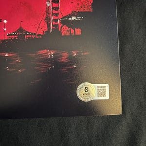 May include: A black and red poster with the word "BOYS" in white text at the top. The poster features a silhouette of a Ferris wheel and a cityscape in the background. The poster has a gold sticker with a QR code and the text "WITNESS AUTOGRAPH" in the bottom right corner.