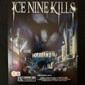 May include: A promotional poster for the band Ice Nine Kills. The poster features a dark, ominous cityscape with the band's name in large, bold letters. The poster also includes the text "You'll never make it in this town..." and "Welcome to Horrorwood".