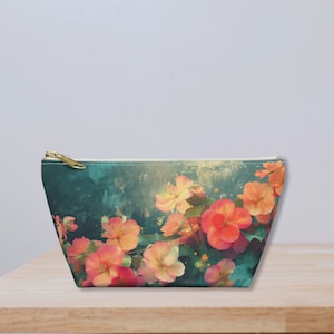 May include: A teal blue zippered pouch with a floral print featuring pink and orange flowers. The flowers are on a teal blue background with a watercolor effect.