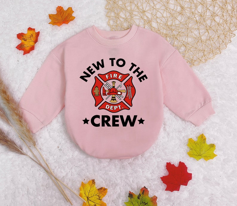 May include: Pink sweatshirt with a black graphic of a fire department logo and the text "New to the Crew".