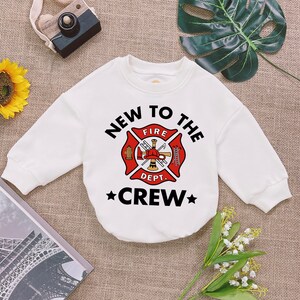 May include: White long-sleeved sweatshirt with a black and red firefighter graphic and the text "New to the Crew".