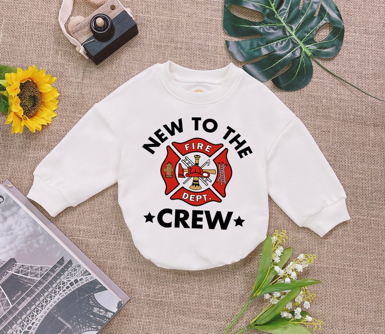 May include: White long-sleeved sweatshirt with a black and red firefighter graphic and the text "New to the Crew".