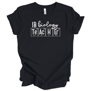 Puede incluir: Camiseta negra con texto blanco que dice "IB Biology Teacher" con las letras "TEACHER" representadas por los símbolos químicos de los elementos Te, Ac, H, Er.
