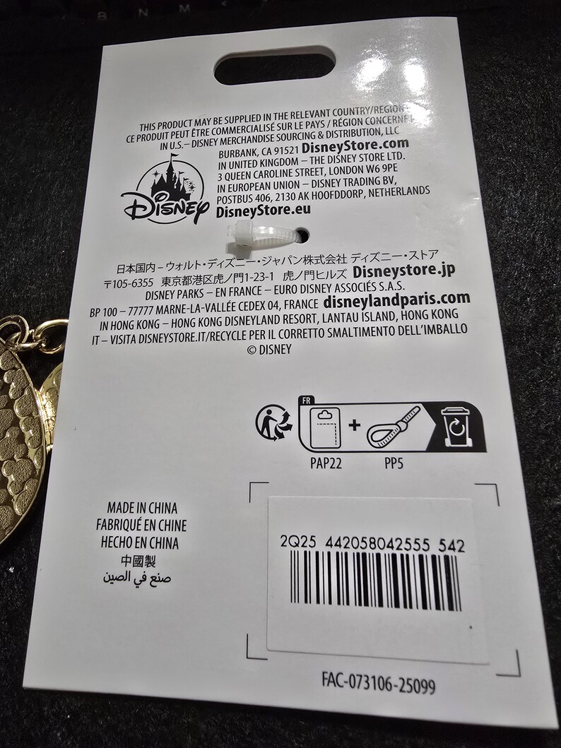 Puede incluir: Una etiqueta de producto blanca con el logotipo de Disney y texto en varios idiomas. La etiqueta incluye un c&oacute;digo de barras, s&iacute;mbolos de reciclaje y el texto "HECHO EN CHINA".