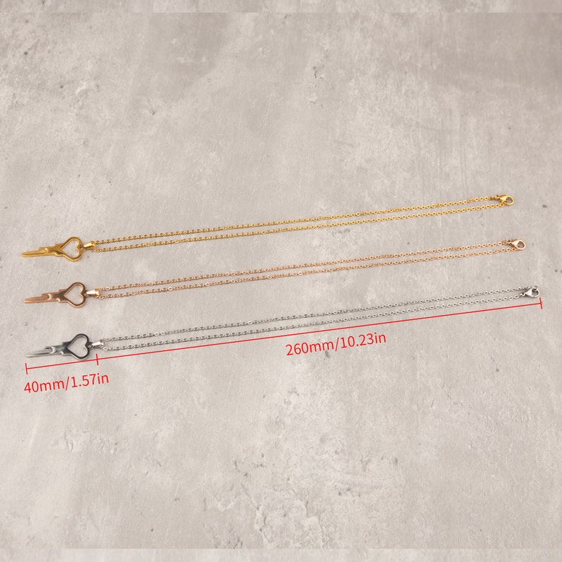 Puede incluir: Tres delicados collares con un colgante en forma de coraz&oacute;n en forma de tijeras. Los collares son de oro, oro rosa y plata. Los collares miden 260 mm de largo y el colgante mide 40 mm de largo.