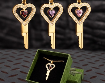 Collar con colgante de llave en forma de jaula con forma de corazón de oro y piedras preciosas.
