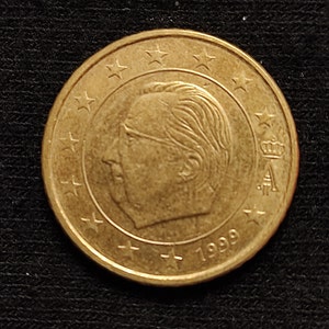 Può includere: Una moneta da 1 euro dorata con il profilo del re Alberto II del Belgio, con l'anno 1999 inciso in basso.
