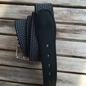 Könnte beinhalten: Ein schwarzer Ledergürtel mit einem blau-schwarzen gemusterten Riemen. Der Gürtel hat eine silberne Schnalle und drei Löcher zum Einstellen der Passform.