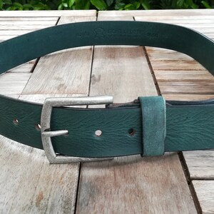 May include: A dark green leather belt with a silver buckle. The belt is made of full grain leather and has a smooth finish. The buckle is a simple, rectangular design.