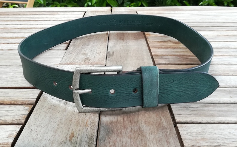 May include: A dark green leather belt with a silver buckle. The belt is made of full grain leather and has a smooth finish. The buckle is a simple, rectangular design.