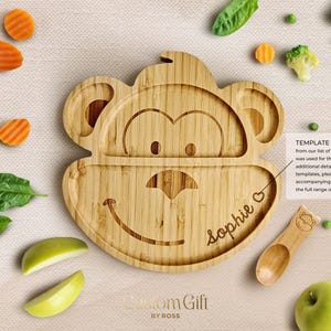 May include: A wooden monkey-shaped divided plate with a smiling face and the name "Sophie" engraved on the bottom section. The plate is made of bamboo and is designed for children.