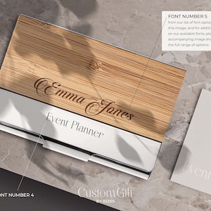 Könnte beinhalten: Ein Visitenkartenhalter aus Holz mit silbernem Metallrand. Der Kartenhalter trägt den Text "Emma Jones" und "Event Planner" eingraviert. Der Text "Custom Gift by Ross" ist unten auf dem Halter aufgedruckt.