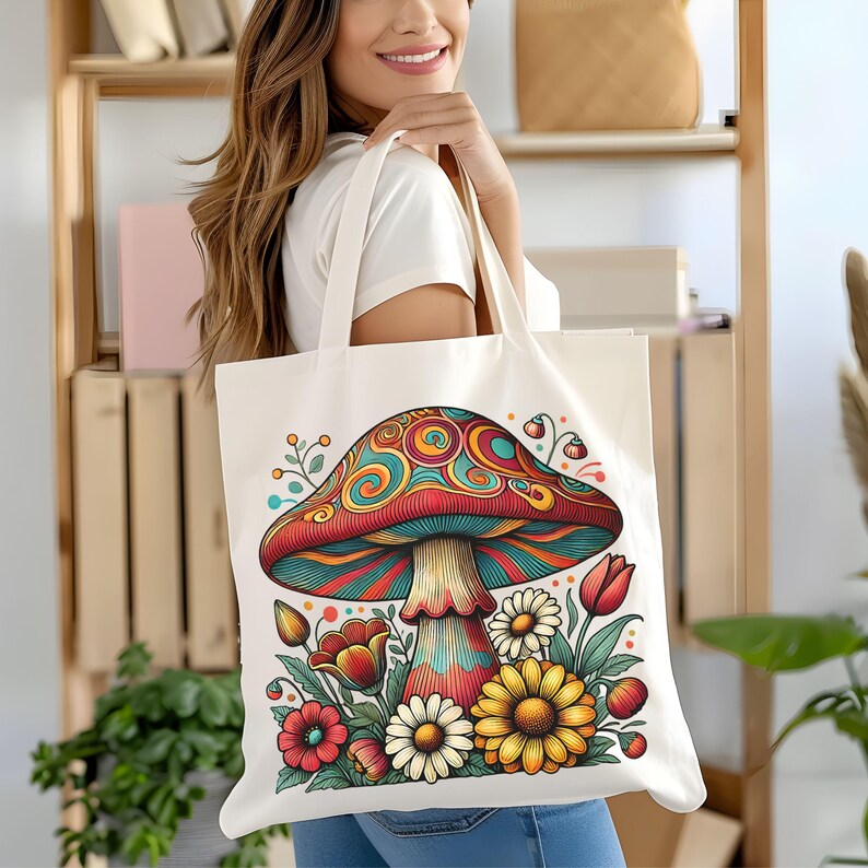 May include: A white canvas tote bag with a colorful psychedelic mushroom design. The mushroom is surrounded by flowers and leaves. The bag has a long handle.