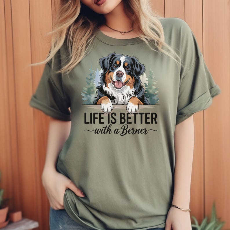 May include: Green t-shirt with a graphic of a Bernese Mountain Dog peeking over a sign that reads "Life is better with a Berner".