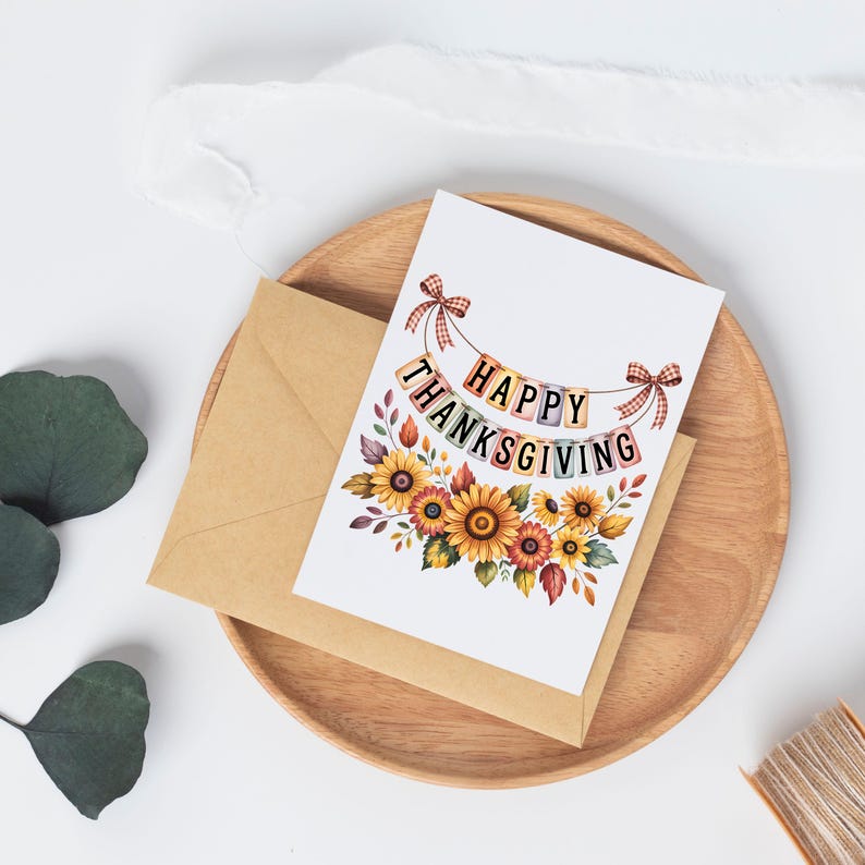 Op de afbeelding: Thanksgiving-wenskaart met zonnebloemen en de tekst "Happy Thanksgiving" op een banner. De kaart ligt op een houten bord met een bruine envelop. De kaart heeft een bloemenontwerp met gele, oranje en rode bloemen.