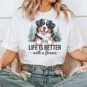 May include: White t-shirt with a graphic of a Bernese Mountain Dog peeking over a sign that reads "Life is better with a Berner".