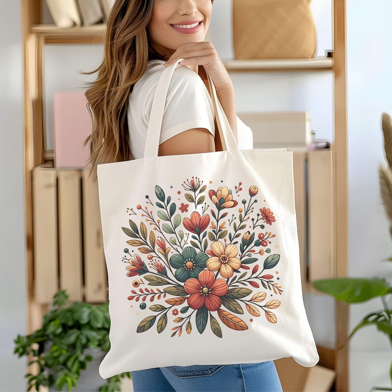 Peut inclure: Un sac fourre-tout en toile blanche avec un motif floral. Les fleurs sont dans des tons d'orange, jaune, rouge et vert. Le sac a deux anses.