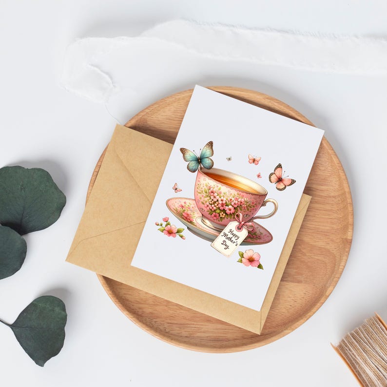 Puede incluir: Una tarjeta blanca con una taza de t&eacute; rosa y un platillo con un dise&ntilde;o floral. La taza de t&eacute; tiene una etiqueta que dice "Feliz D&iacute;a de la Madre". Hay mariposas y flores alrededor de la taza de t&eacute;.