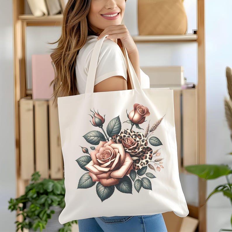 May include: Cream-colored tote bag featuring a floral design with roses, buds, and leaves in shades of peach, brown, and green. A leopard print rose adds a unique touch to the design. The bag has long handles for carrying.