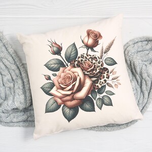 May include: Cream-colored square throw pillow featuring a floral design. The design includes large, open roses in shades of peach and brown, with green leaves and a leopard print rose. The pillow is on a white wooden surface.