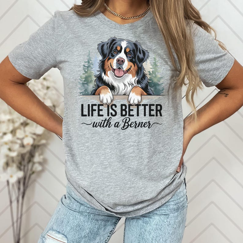 May include: A gray t-shirt with a graphic of a Bernese Mountain Dog peeking over a wooden sign. The sign reads "Life is better with a Berner".