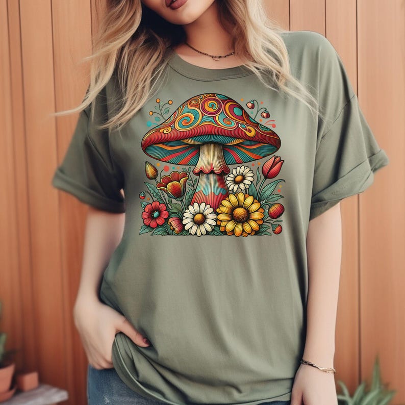 May include: A green t-shirt with a colorful mushroom and flowers graphic. The mushroom has red, yellow, blue, and green swirls. The flowers are red, yellow, and white.