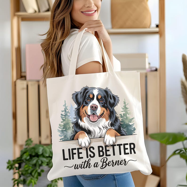 May include: White canvas tote bag with a cartoon illustration of a Bernese Mountain Dog peeking over a wooden sign. The sign reads "Life is better with a Berner".