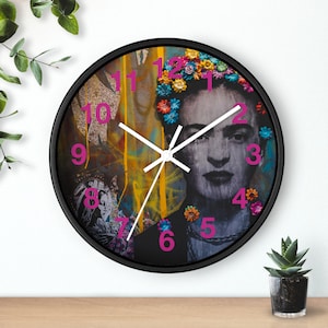 May include: A black framed clock with a colorful image of Frida Kahlo. The clock face has pink numbers and white hands.