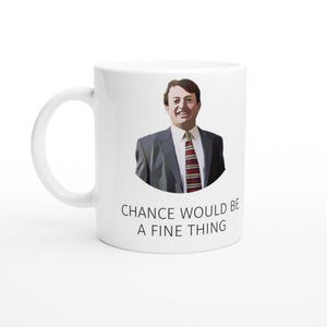 Op de afbeelding: Witte keramische mok met een lachende man in pak en stropdas. De mok heeft de tekst "CHANCE WOULD BE A FINE THING" in zwarte letters. De mok heeft een standaard formaat met een gebogen handvat.