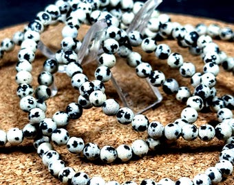 May include: A set of black and white speckled stone bracelets. The bracelets are made of small, round beads and are stacked on top of each other.