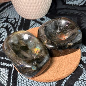 May include: A set of three ceramic mugs with a speckled, matte finish. The mugs are in shades of cream, light gray, and dark gray. Each mug has a simple, minimalist design and a rounded handle. The mugs are stacked on top of each other.