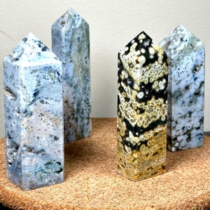 May include: Four stone obelisks with varying patterns and colors. Three are primarily blue and white with speckled designs, while the fourth features a black, white, and gold pattern. The obelisks are rectangular with pointed tops.