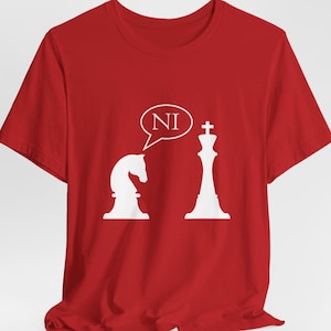 May include: Red t-shirt with a white chess knight and king graphic. The knight is saying "NI" in a speech bubble.