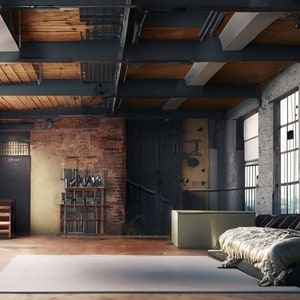 May include: A large, modern bed with a gray headboard and a white comforter sits in a loft-style room with exposed brick walls and large windows. The room has a rustic, industrial feel.