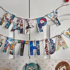 May include: A colorful "Happy Birthday" banner with anime characters on each letter. The banner is strung on a white wall.