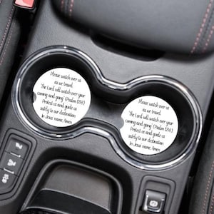 May include: Two white car coasters with black text that reads "Please watch over us as we travel. "The Lord will watch over your coming and going" (Psalm 121:8) Protect us and guide us safely to our destination. In Jesus name, Amen."