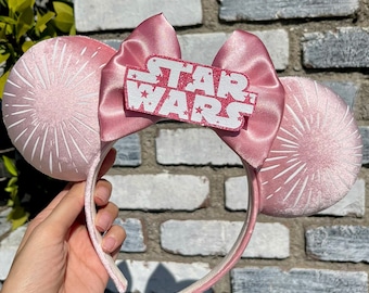 May include: Pink velvet mouse ears with a white starburst design and a pink satin bow with a glitter "STAR WARS" patch.