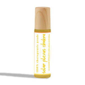 May include: A glass roller bottle with a wooden cap and a yellow label that reads "100% therapeutic grade solar plexus chakra an essential oil blend for solar plexus activation."