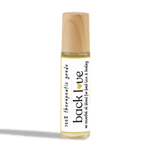May include: A small, clear glass bottle with a wooden cap and a white label. The label says "100% therapeutic grade back love an essential oil blend for back love & healing".