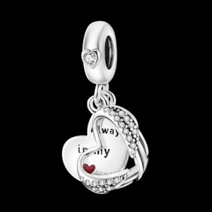 Può includere: Ciondolo in argento con due cuori intrecciati. Il cuore più grande ha un'aureola di cristallo trasparente e l'iscrizione "Always in my". Il cuore più piccolo è rosso e si trova all'interno del cuore più grande.