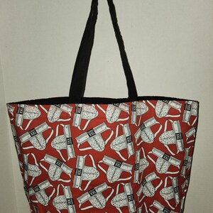 May include: A red tote bag with black straps and a white print of underwear with the text "XXL" repeated throughout.