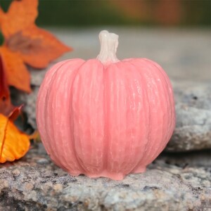 May include: A pink pumpkin-shaped candle with a textured surface.