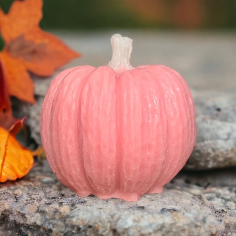 May include: A pink pumpkin-shaped candle with a textured surface.