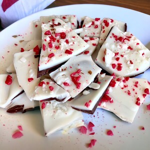 May include: A plate of white chocolate bark broken into pieces, topped with red sprinkles and white flakes.