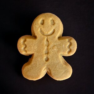 Puede incluir: Una galleta de jengibre con forma de hombre de jengibre con una cara sonriente.