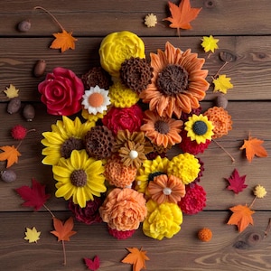 Peut inclure: Un assortiment de savons artisanaux en forme de fleurs colorées, notamment des tournesols, des roses et des dahlias. Les savons sont disposés sur une surface en bois avec des feuilles d'automne et des glands épars, créant un thème automnal.