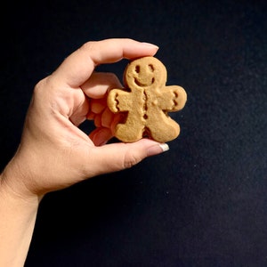 Puede incluir: Una galleta de jengibre con forma de hombre de jengibre sonriente. La galleta es de color marr&oacute;n claro y tiene un dise&ntilde;o sencillo.