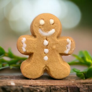 Puede incluir: Una galleta de jengibre en forma de hombre con glaseado blanco y una cara sonriente. La galleta est&aacute; sobre una superficie de madera.
