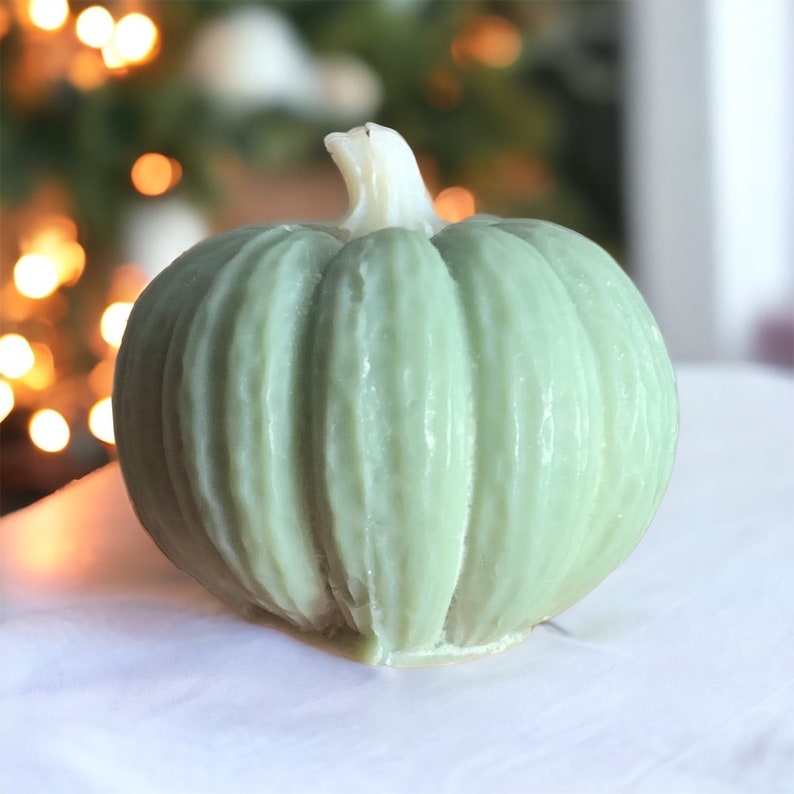May include: A green pumpkin-shaped candle with a ribbed texture.