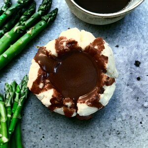 May include: A white cookie shaped like a bowl filled with dark chocolate sauce.